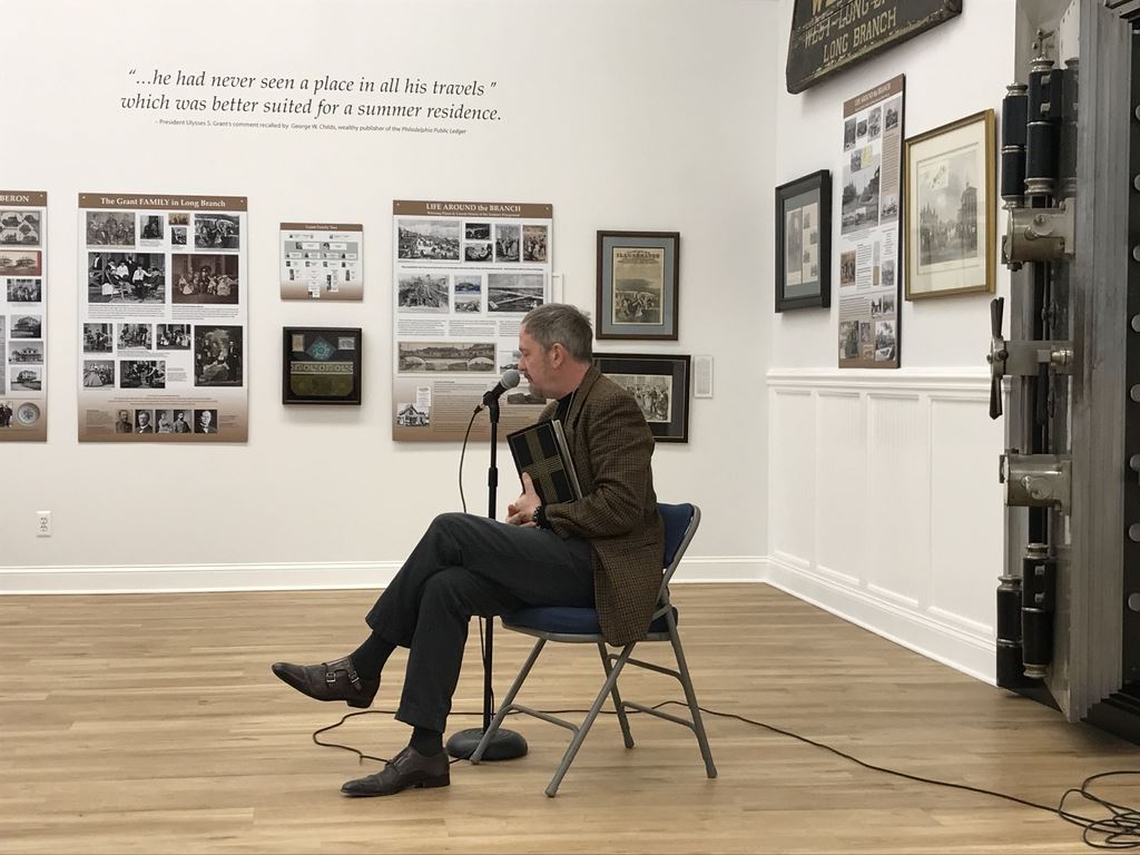 Comedy Night - Joe sitting in chair holding book