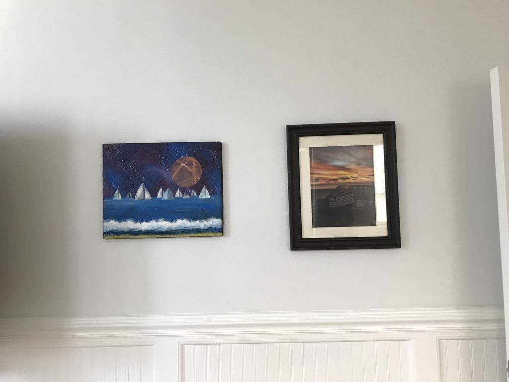 Close-up of paintings of sailboats and photo of sunset